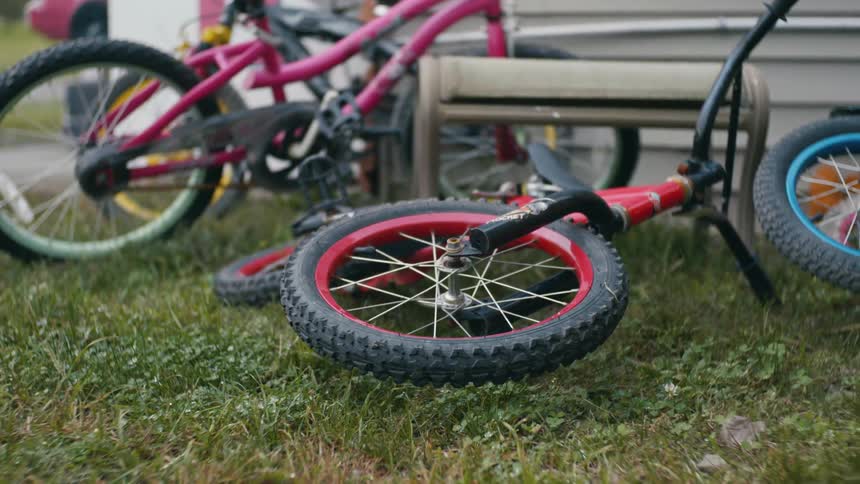 Childrens bicycles lying on grass next to a building
