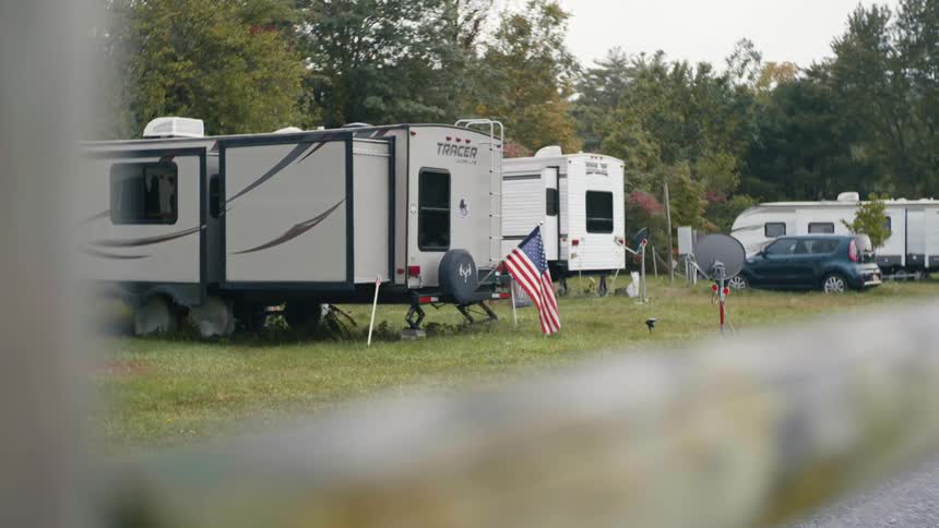 Mobile homes parked in a trailer park while an american flag hangs from the back of one