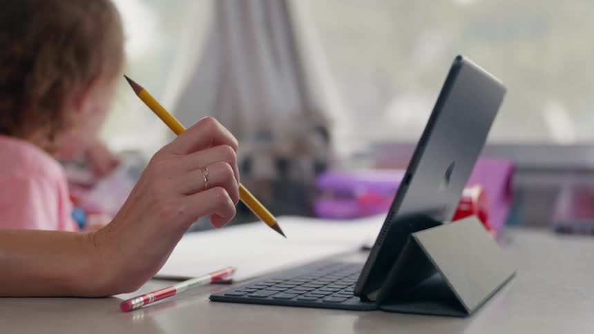 A person using a laptop with a paper and pencil
