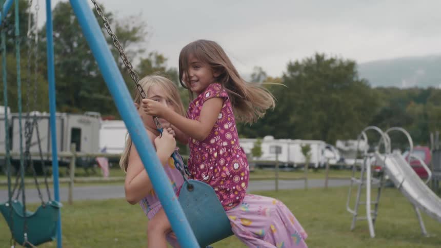 Girls in wearing dresses playing in the swings on the trailer park