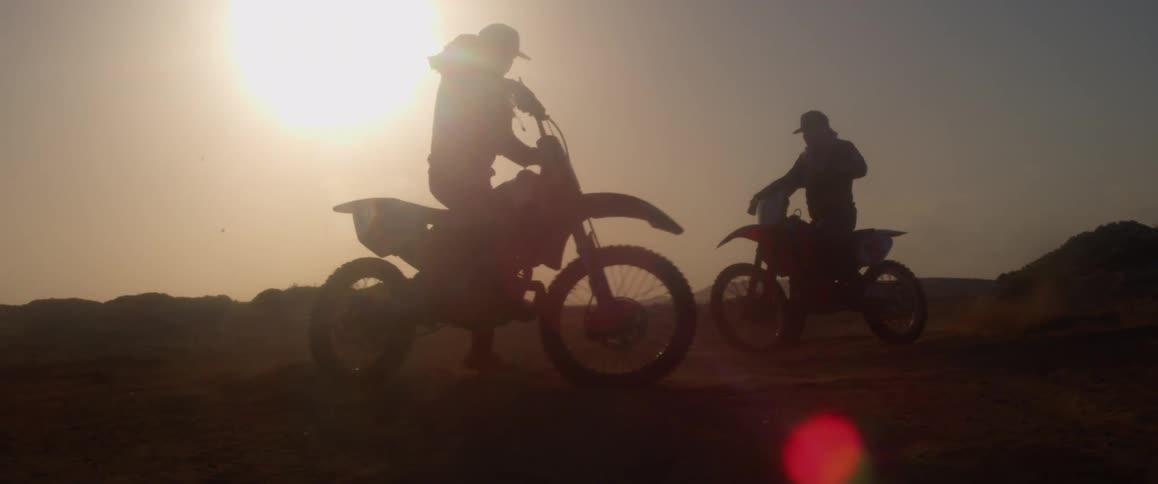 Two men are riding bikes outdoors at dusk