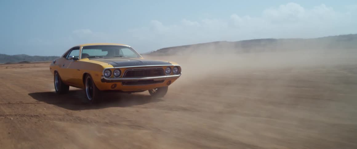 Yellow and black mustang driving on a flat desert plain at daytime