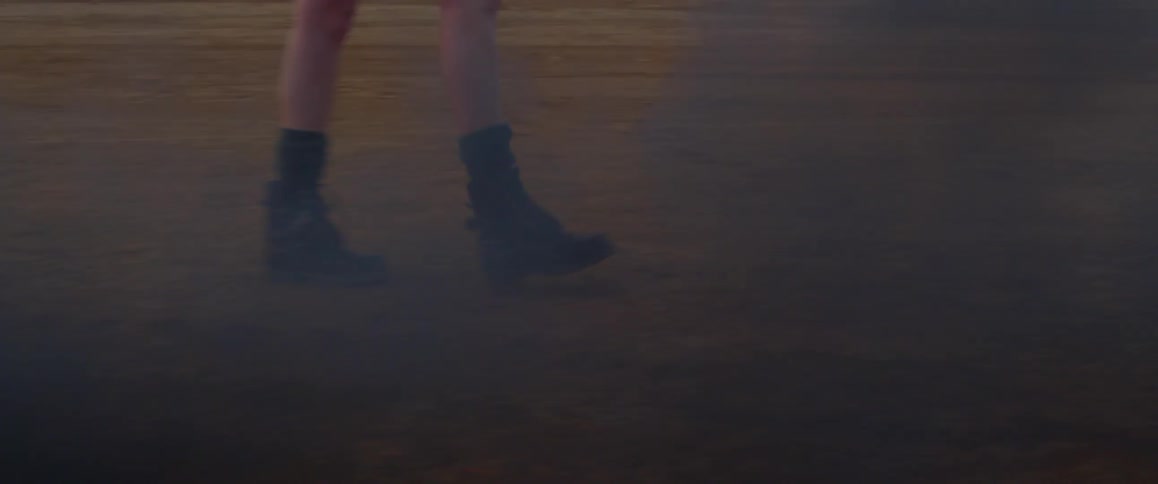 A woman walks past a fire burning in a pit outside