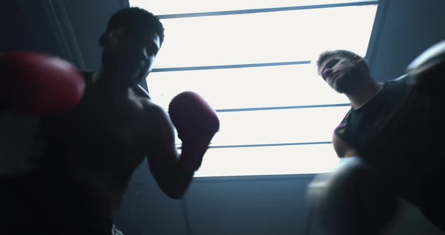 Two men are boxing each other indoors