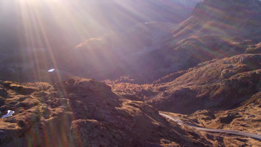 Car driving on a road through a valley in the mountains at sunset