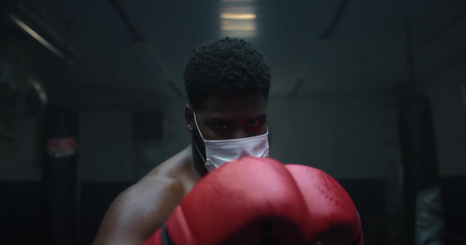 Male boxer with a white mask and boxing gloves in the gym