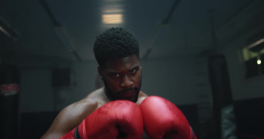 Shirtless muscular strong boxer throwing punches at the camera
