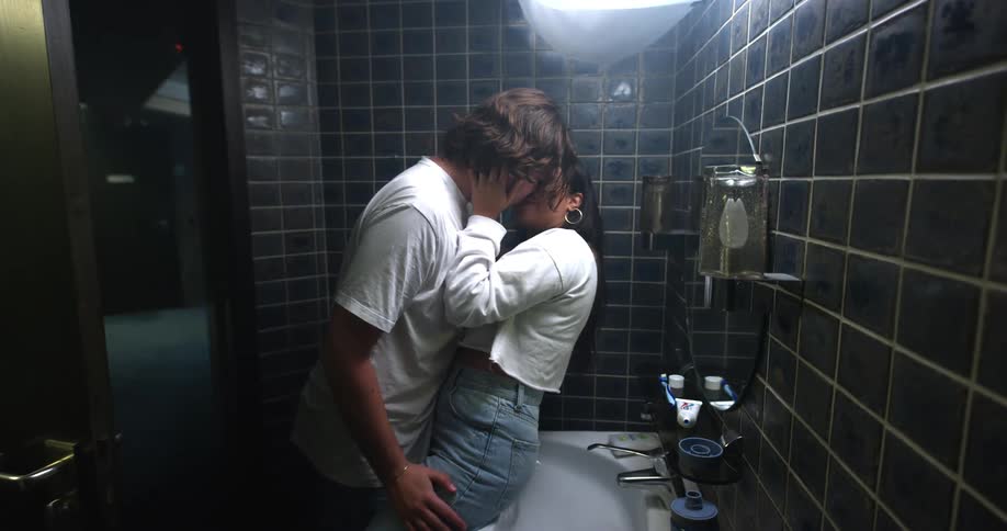 Man and woman kiss each other passionately in the restroom