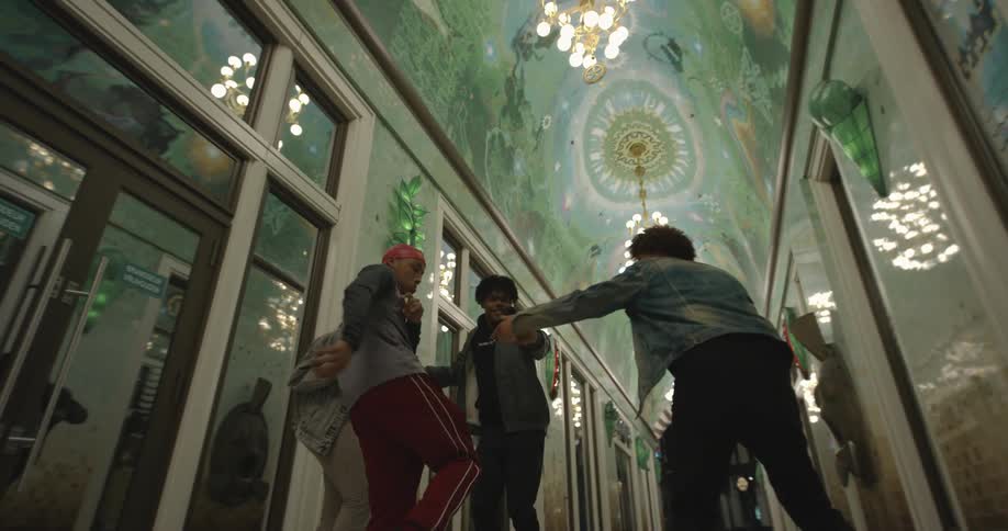 Men and women dance in a hallway inside a building with an ornate ceiling