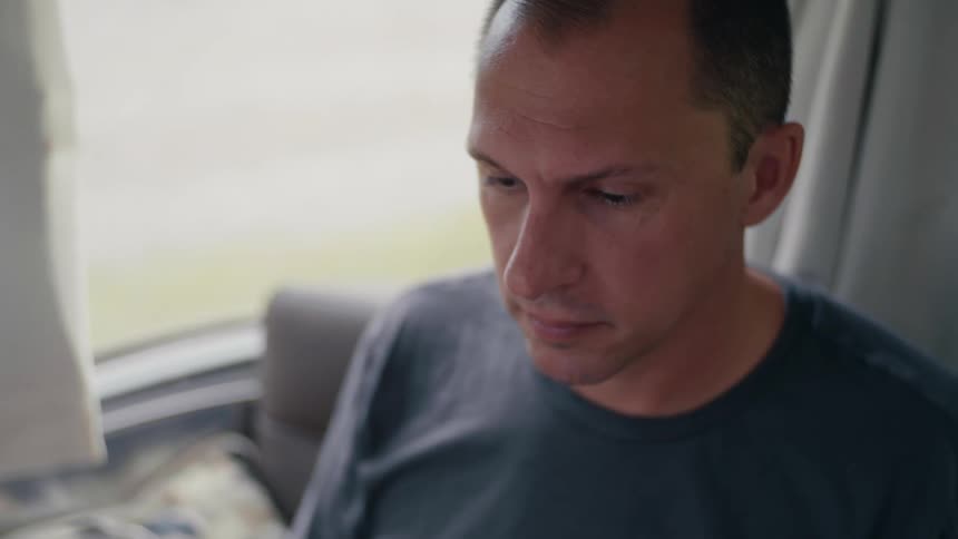 A man sitting on a chair in a room with a window in the background