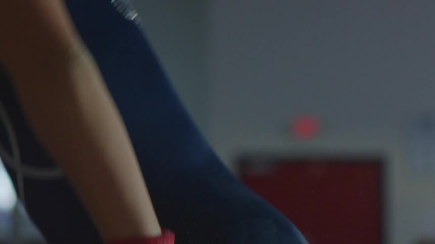 A gymnast grabs onto uneven bars and holds herself in a headstand