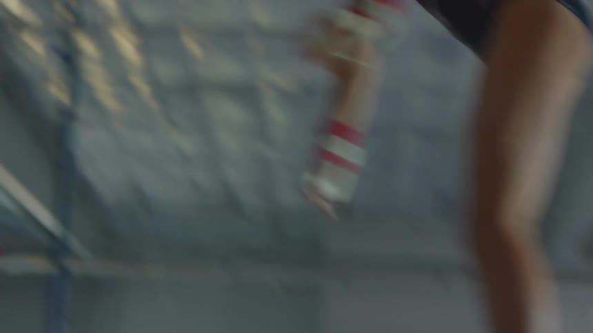 A teenage girl does a flip on a gymnastic bar inside a gym