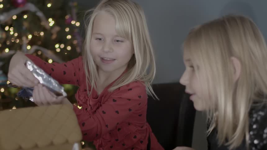 A little girl squeezing frosting on a gingerbread house