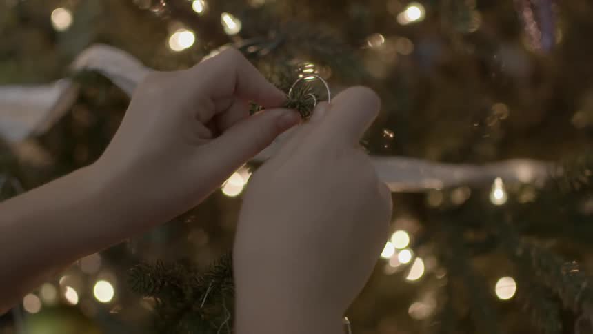 Someone putting an ornament on a christmas tree