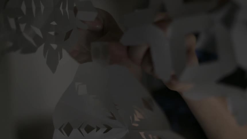 A boy taping paper snowflakes to a window