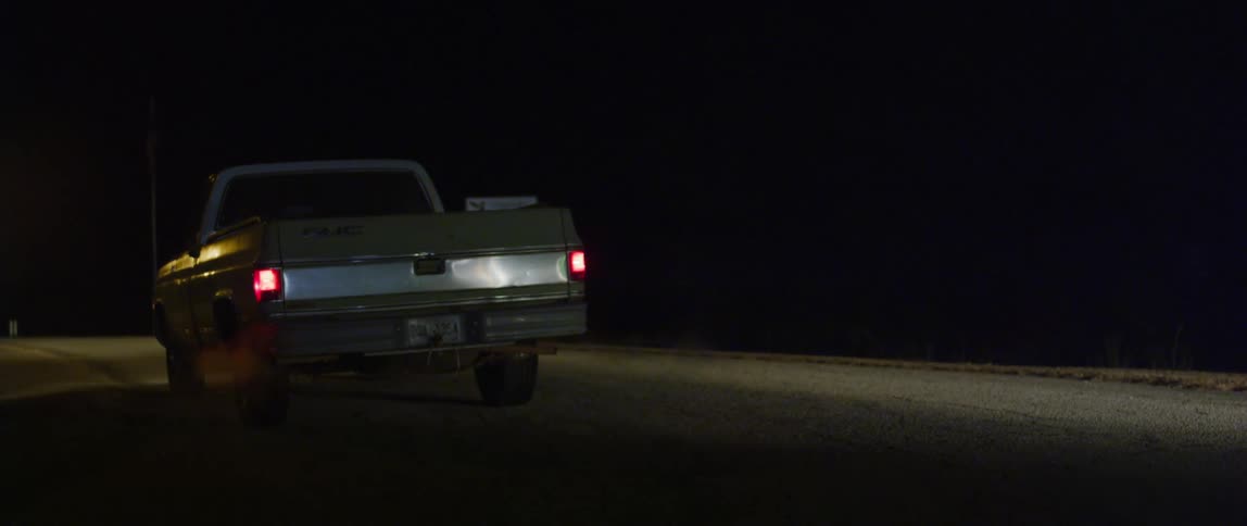 A pickup truck is driving outdoors at night