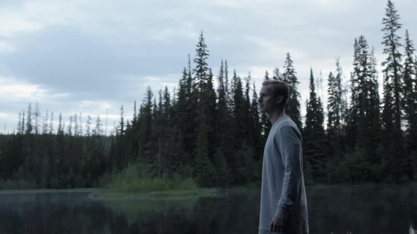 A man is standing by a lake looking around