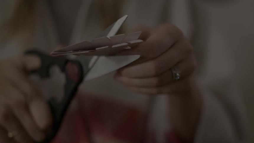 A woman is cutting some paper with scissors