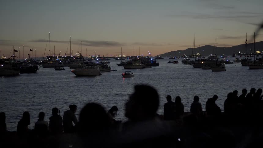 A large number of boats are docked in the water at sunset