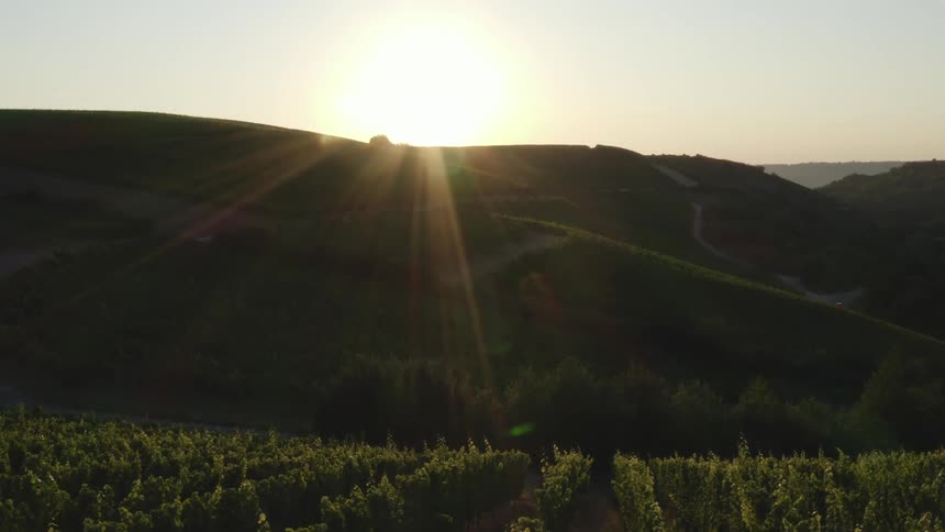 The sun is setting in the horizon above the hills