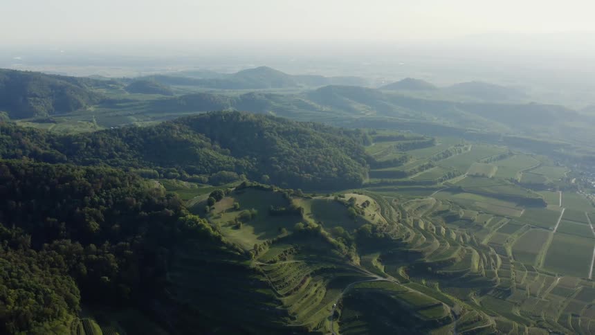 An aerial view of green hills with a misty sky during the day