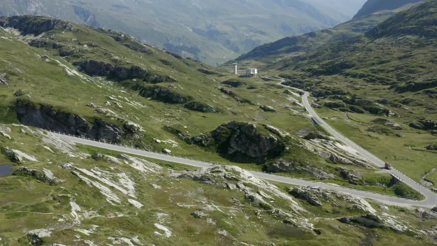A rural area with a car and bike on a road through a countryside with grass and rocks