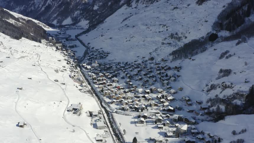 A snow covered town in a valley between the two mountains