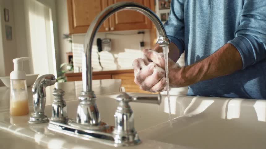 A person washing their hands in a sink in the kitchen