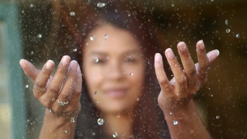 A woman is standing outdoors while its raining