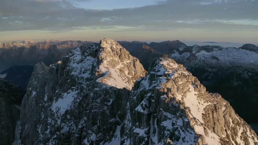 Aerial view of snow covered peaks in a mountain range at sunset
