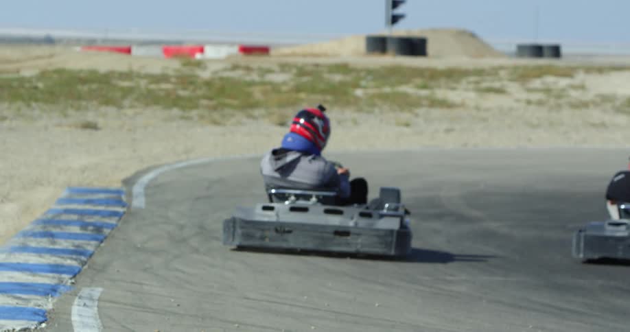 A group of go carts taking a curve on a race track at day
