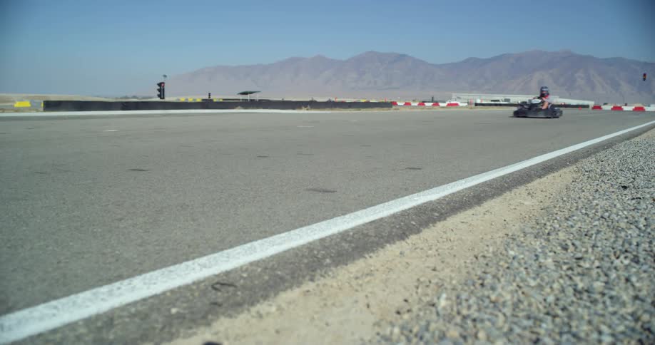 People on go karts racing around a speedway track at day time