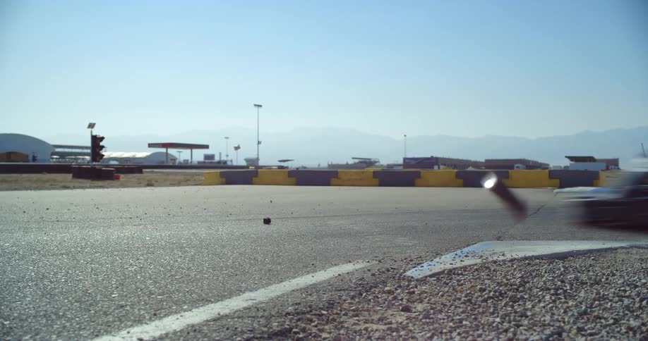 Several people driving go karts race around a corner at a racetrack