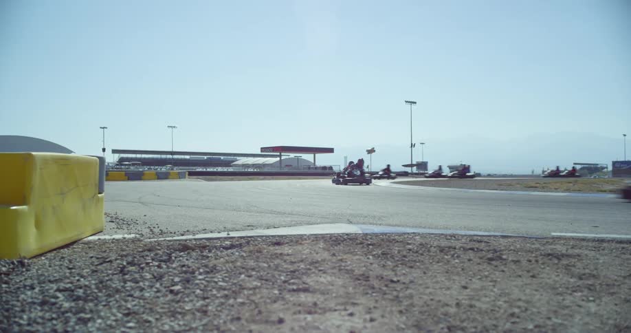 A group of go cart taking a curve on a race track at day