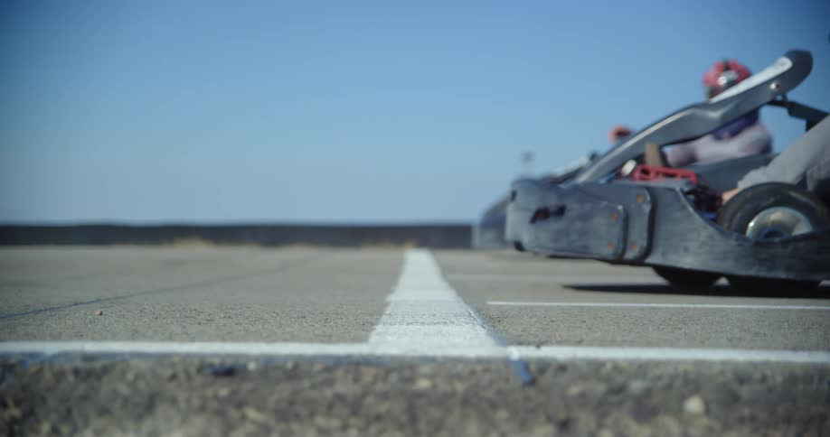 A pair of people pull up to the starting line on a race track in go karts