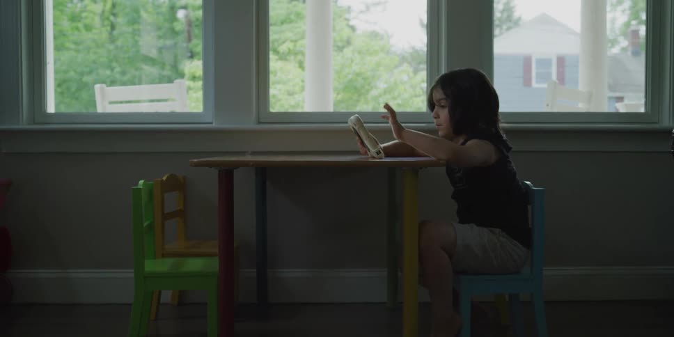 Boy on a tablet sitting at a mini table next to a window in a home