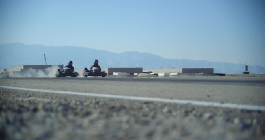 Competing go carts driving over the curves of a race track at day