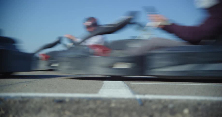 Men at a startline on a race track racing in go karts in the afternoon