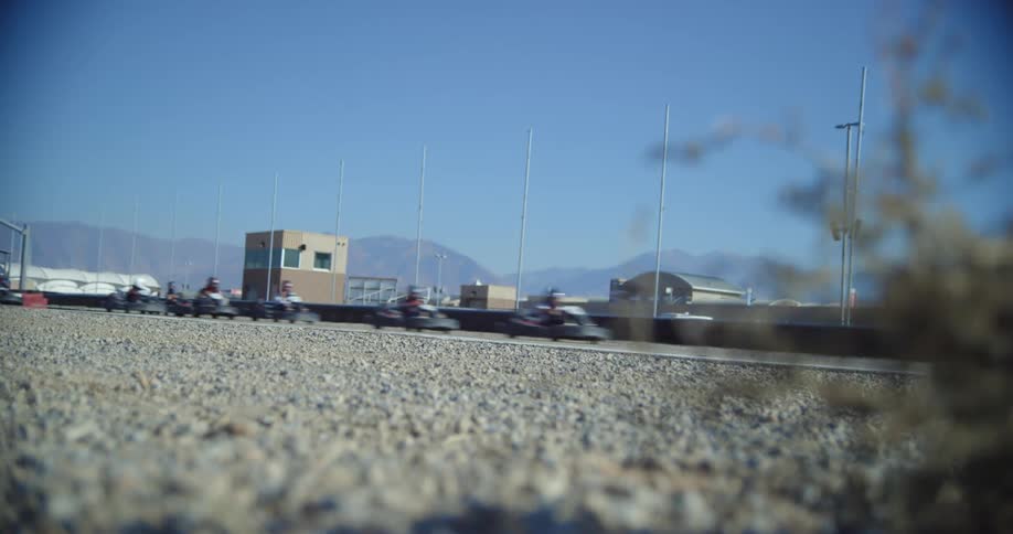 People race on a go cart track in a sunny day with a bright blur sky with buildings in the back ground