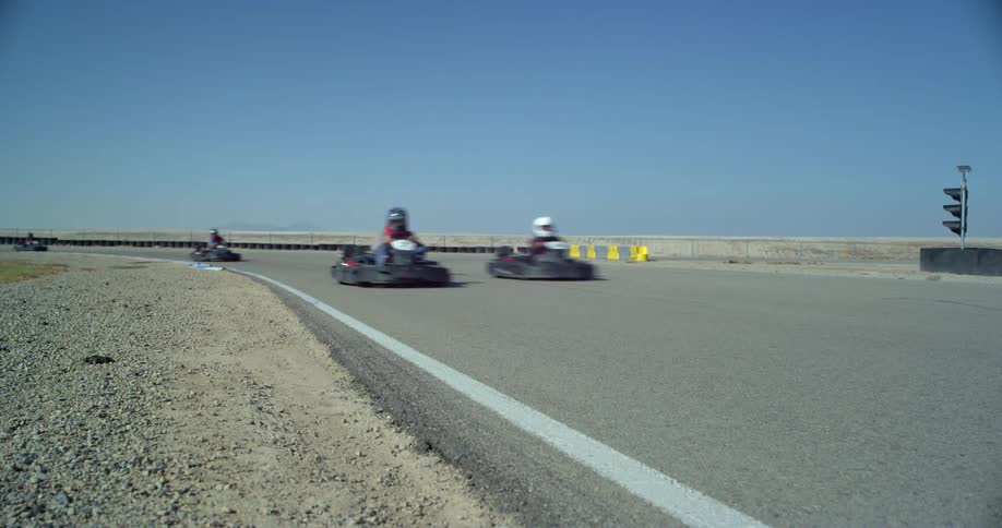 Bumper cars speed by on an outdoor track on a bright blue sky day
