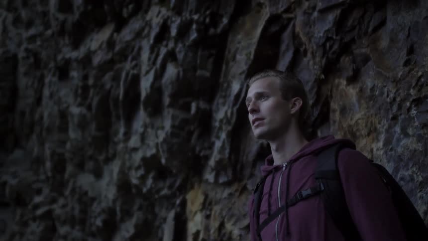A man looking into the distance as he stands next to a cliff