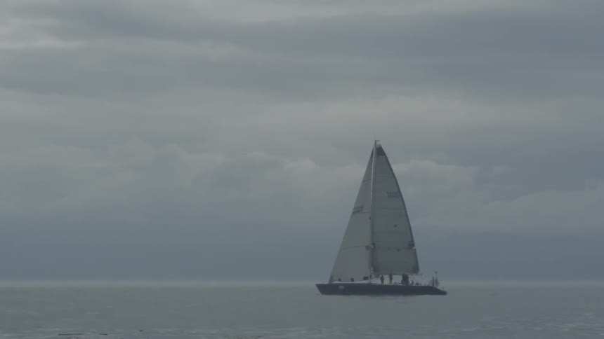 A boat is sailing in the water on a cloudy day