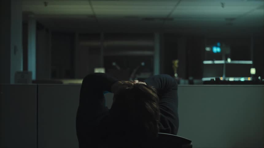 Man tilts his head and puts his hands on his face while sitting in a chair