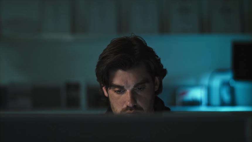 A man sitting in a room in front of a computer screen