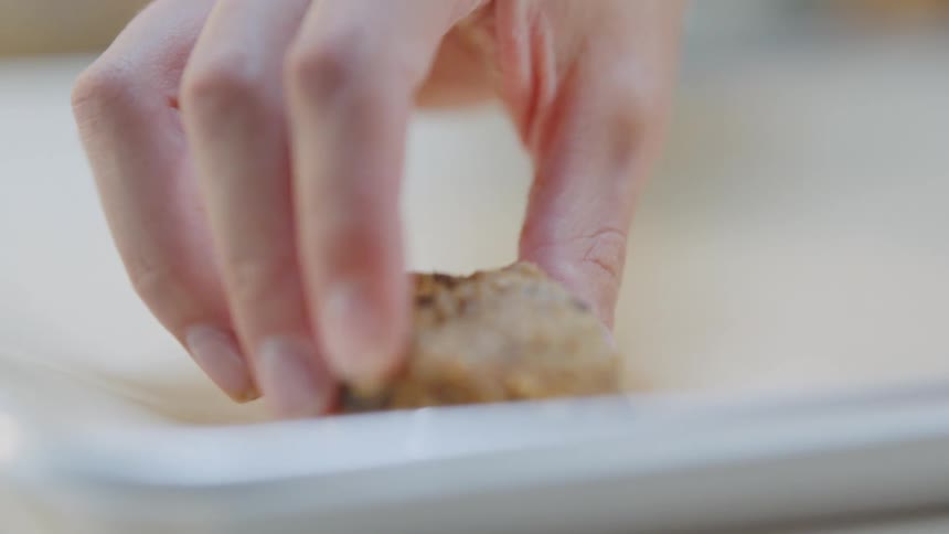 A person is placing cookie dough on the pan