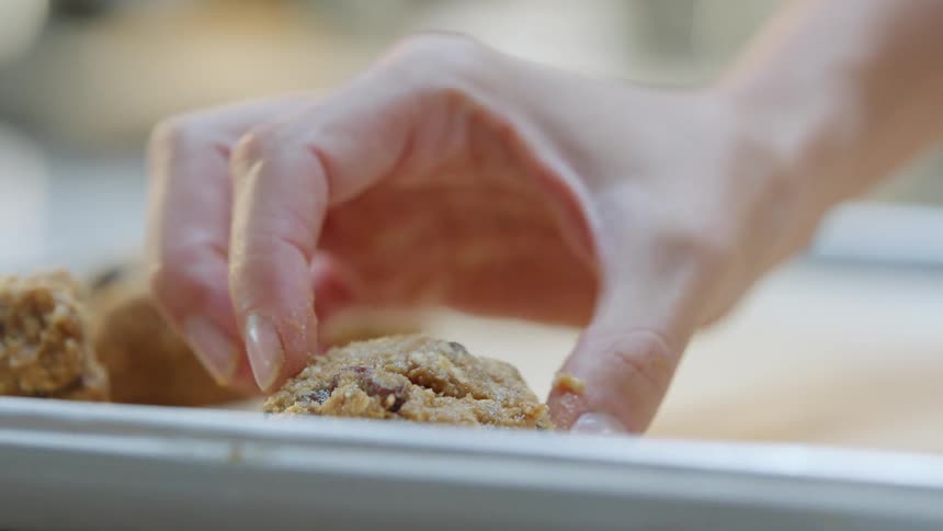 A woman places mound of cookie dough evenly spaced on a cookie sheet