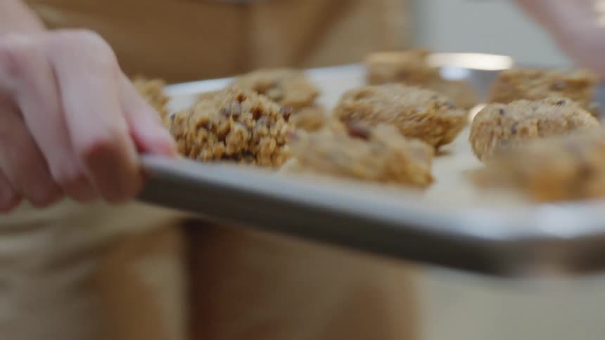 A woman places a baking sheet of cookies in the oven