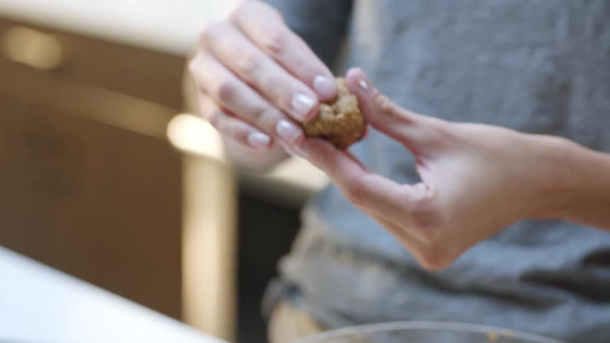Woman rolling cookie dough into a ball and putting it on a baking sheet