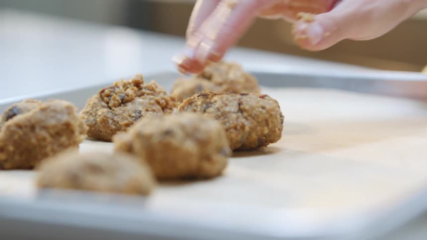 Cookie dough being placed on a baking sheet in a home kitchen