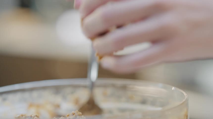 Hands scooping cookie dough off a spoon and rolling into a ball